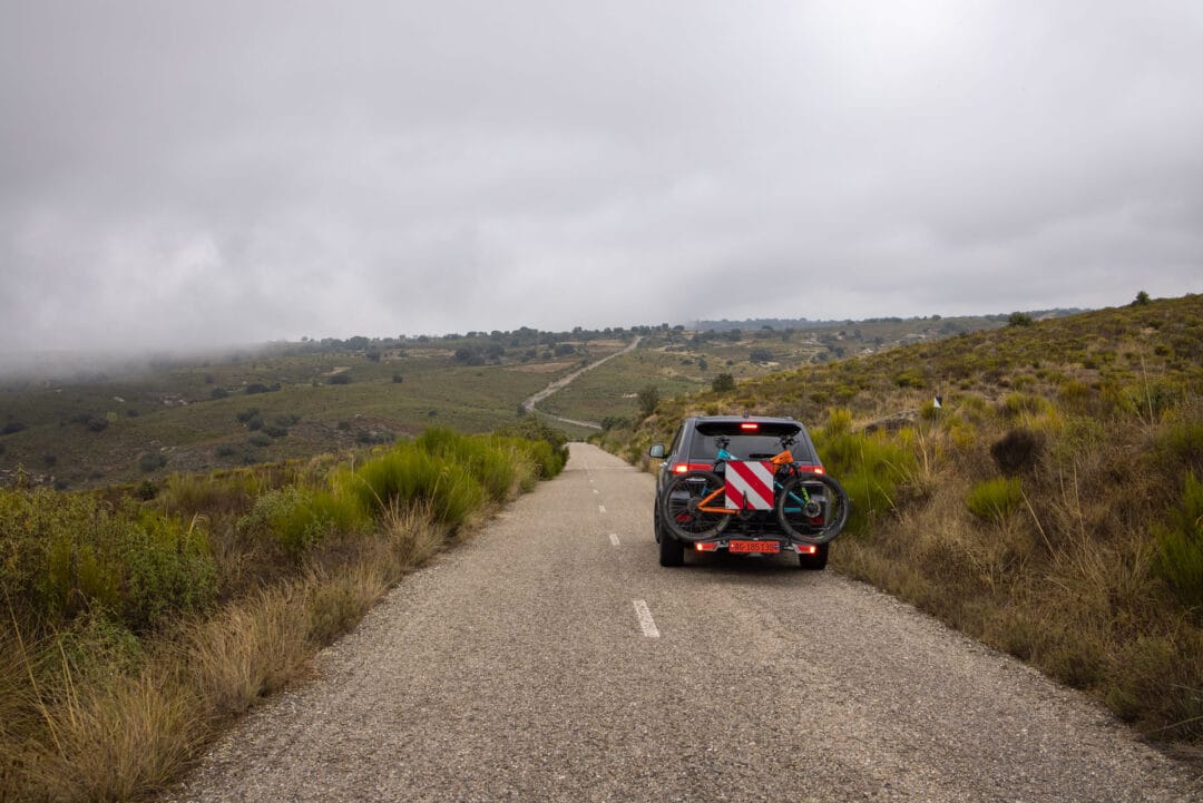 Roadtrip durch Kastilien-León: Auto mit E-Bikes auf einer einsamen Landstraße in der wilden Natur Spaniens.